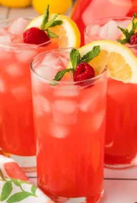 Refreshing peach raspberry lemonade in a glass with lemon slices and raspberries