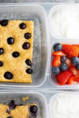 Sheet pan protein pancakes stacked on a plate, garnished with berries and syrup.