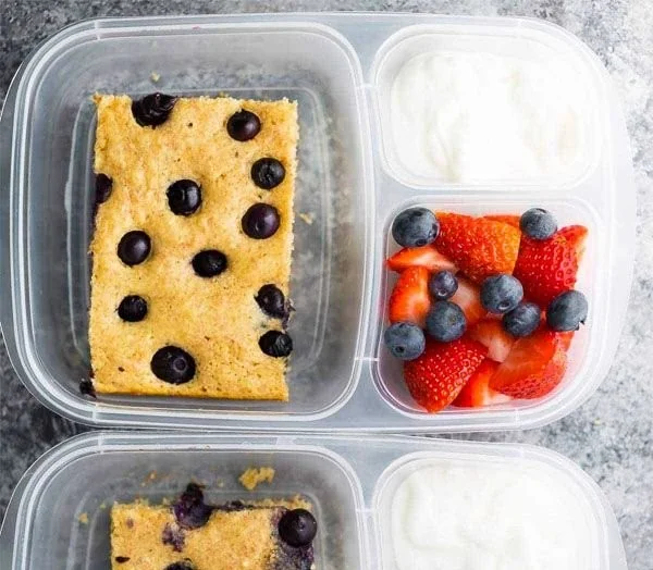 Sheet pan protein pancakes stacked on a plate, garnished with berries and syrup.
