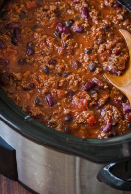 A bowl of delicious slow cooker chili topped with fresh herbs and cheese.