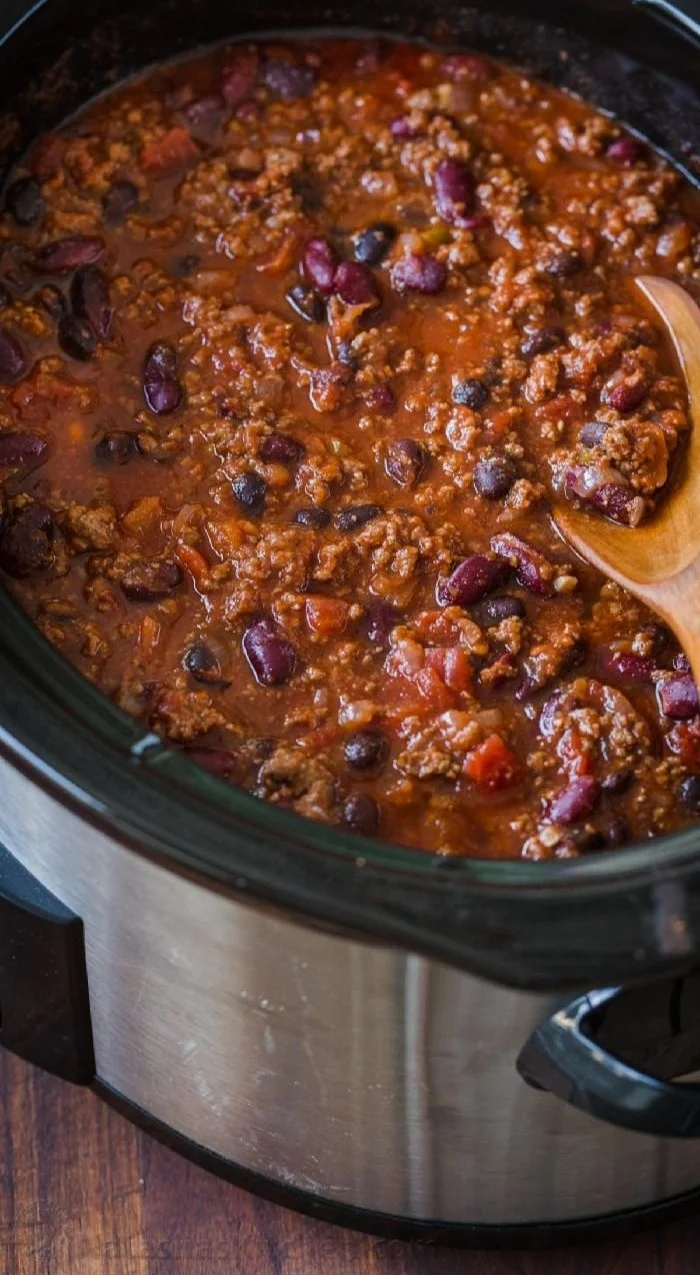 A bowl of delicious slow cooker chili topped with fresh herbs and cheese.