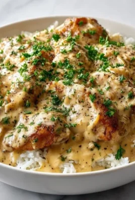 Plate of Smothered Chicken served over rice with rich gravy and vegetables