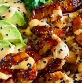 Teriyaki shrimp rice bowls garnished with vegetables and sesame seeds.