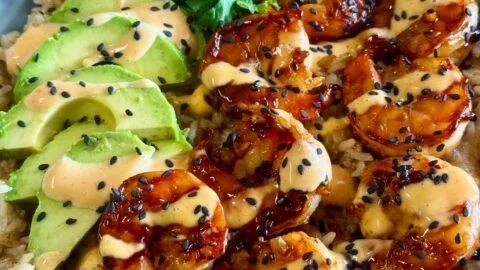 Teriyaki shrimp rice bowls garnished with vegetables and sesame seeds.