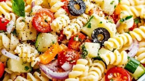 Colorful bowl of ultimate pasta salad with cherry tomatoes and basil