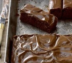 Delicious zucchini brownies topped with chocolate frosting on a wooden table