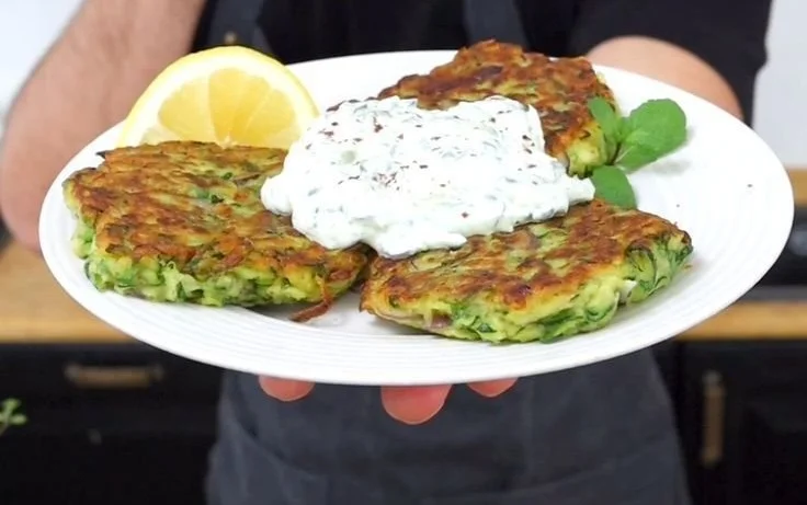 Golden crispy zucchini fritters served on a plate with dipping sauce